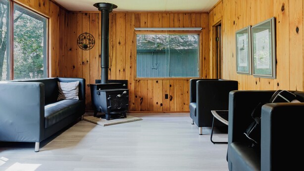 A wooden-paneled room with a fireplace, two sofas, and a ceiling light. - 3 Bedroom Cottage V: SB (Carling)