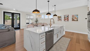 Una cocina moderna con una isla central, iluminación colgante y un comedor con sofá y sillas.