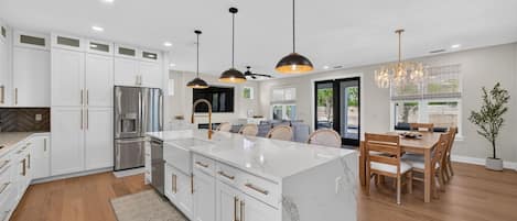A modern kitchen with white cabinetry, a central island, and pendant lighting.