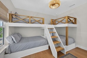A bunk bed room with a ladder, a window, and a woven light fixture. - Luxury Beach Retreat I Heated Saltwater Pool (Saint Augustine)