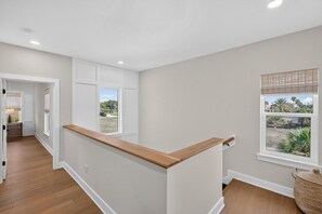 A modern interior with a wooden bench, a window with a view, and a door leading to another room. - Luxury Beach Retreat I Heated Saltwater Pool (Saint Augustine)