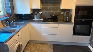 Cuina compacta amb rentadora, fogó, cafetera i forn encastrat.