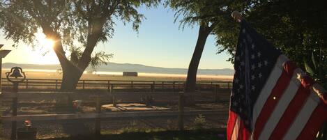 A park with a bench, an American flag, and a view of a body of water.