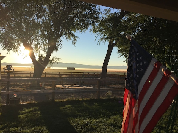 A park with a bench, an American flag, and a view of a body of water.