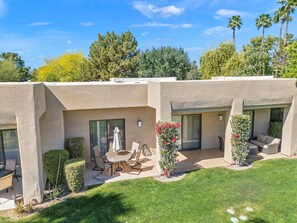 A residential property with a patio area, outdoor furniture, and a well-maintained lawn. - Your Perfect Desert Retreat -Relax and Recharge in a fully remodeled 2 bed condo (Palm Springs)