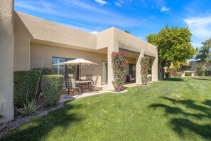 A residential building with a patio area, outdoor seating, and a well-maintained lawn. - Your Perfect Desert Retreat -Relax and Recharge in a fully remodeled 2 bed condo (Palm Springs)