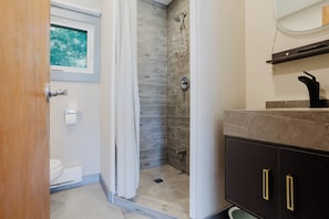 Een badkamer met douche, toilet en wastafel met spiegel.