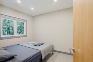 Un dormitori amb llit, finestra i vistes, i una porta.