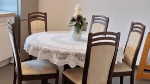 Comedor con una mesa redonda, cuatro sillas, un refrigerador y una planta pequeña.