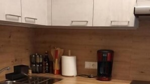 Una cocina con armarios blancos, encimera de madera, lavavajillas y cafetera.