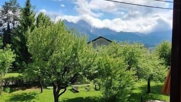 Un balcón con vistas a un paisaje verde y un edificio lejano.