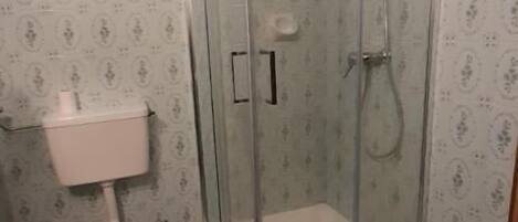 Ett badrum med en dusch som är avskärmad med glasväggar, en toalett och ett badkar.