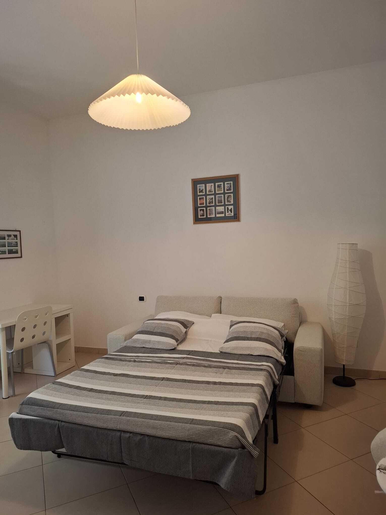 A bedroom with a bed, bedside tables, a lamp, and a framed photo on the wall.