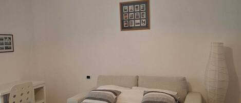 A bedroom with a bed, bedside tables, a lamp, and a framed photo on the wall.