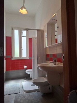 Ein Badezimmer mit Toilette, Waschbecken und Duschbereich.