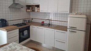 Eine kleine Küche mit weißen Schränken, einer Edelstahl-Spüle und einem schwarzen Backofen.