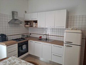 Eine kleine Küche mit weißen Schränken, einer Edelstahl-Spüle und einem schwarzen Backofen.