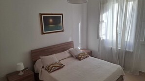 Ein Schlafzimmer mit Bett, Nachttisch, Lampe und einem Bild an der Wand.