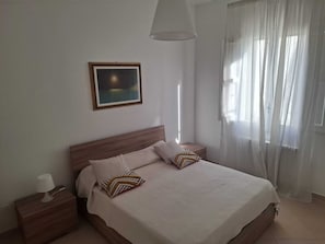Ein Schlafzimmer mit Bett, Nachttisch, Lampe und einem Bild an der Wand.
