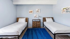 Un dormitorio con dos camas individuales, una mesita de noche de madera y una alfombra azul.