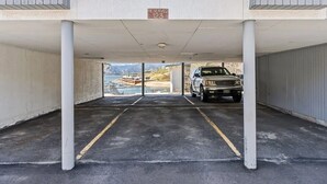 Un estacionamiento con letrero de espacios reservados, pilares de concreto y vista a la playa.