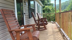 Eine Holzterrasse mit Schaukelstühlen und einem überdachten Veranda-Bereich.