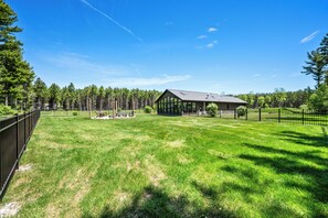 A house with a large lawn, a gazebo, and a forest in the background. - Modern Rustric Retreat w/Fenced Yard + 4-Season Room (Baileys Harbor)