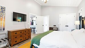 A bedroom with a bed, dresser, TV, ceiling fan, and white doors. - Modern Rustric Retreat w/Fenced Yard + 4-Season Room (Baileys Harbor)