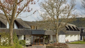 A modern building with a stone facade, large windows, and a paved courtyard. - 2 Person Holiday Park Home in Willingen (Willingen)