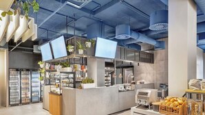 Un área de cocina moderna con electrodomésticos de acero inoxidable, una isla central y una exhibición de pan y pasteles.
