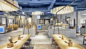 Un restaurante moderno con techos altos, conductos expuestos y una zona central de servicio.