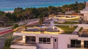 A modern hotel with a rooftop pool, outdoor seating, and a view of the beach. - Coming Soon | O Condo 2 By Bocobay (Noord)