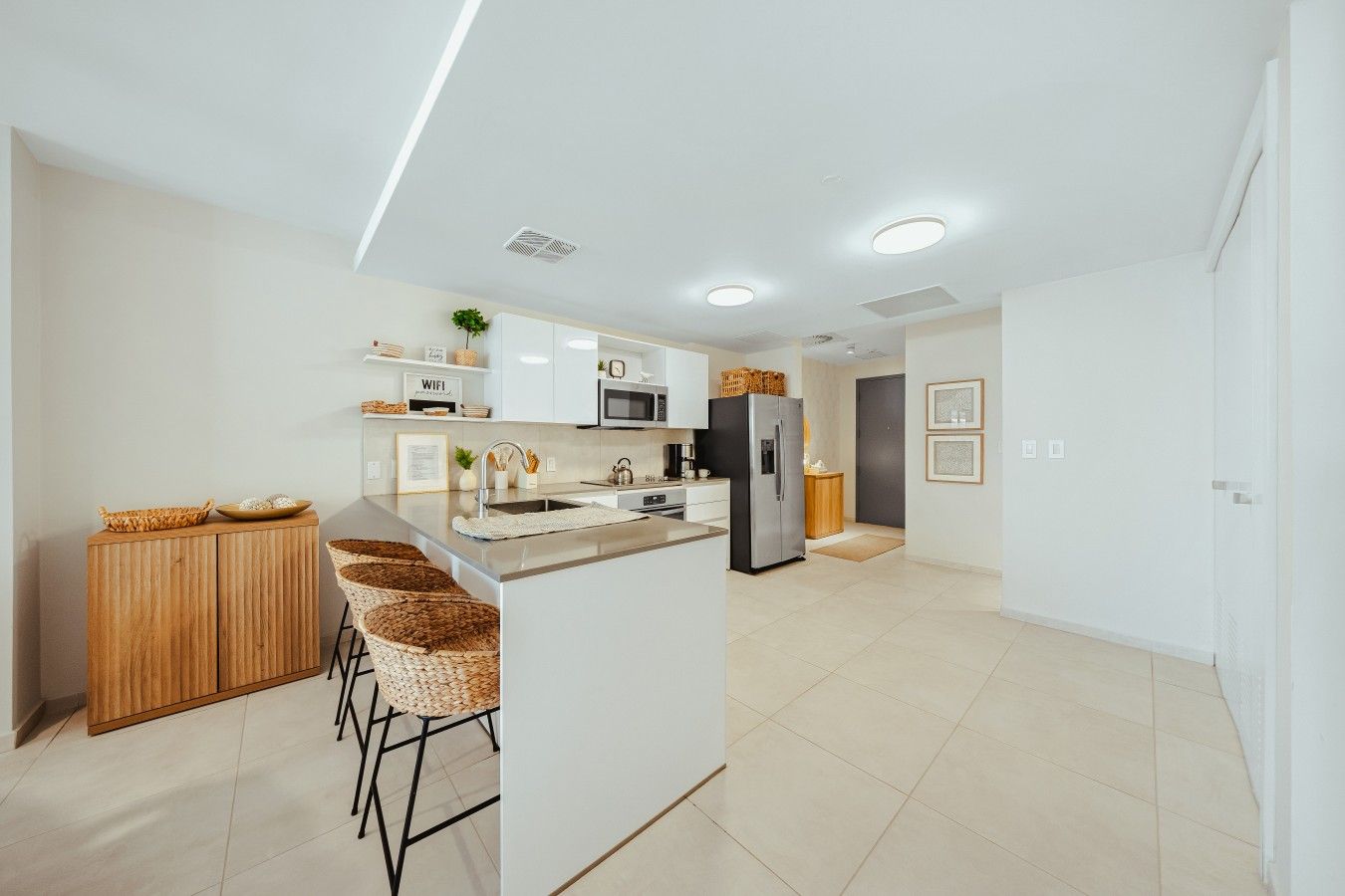 Una cocina moderna con una isla central, taburetes de bar, un refrigerador y un microondas.