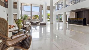 A spacious lobby with high ceilings, a reception desk, and seating areas. - Coming Soon | O Condo 2 By Bocobay (Noord)