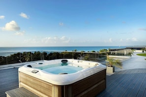 Un bain à remous sur une terrasse en bois, avec vue sur l’océan.