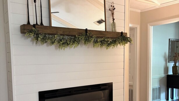 A white paneled wall with a fireplace, a mirror, and a shelf with greenery and candles. - Relax and Unwind near West Point Lake (LaGrange)