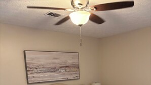 A hotel room with a bed, two bedside lamps, a ceiling fan, a painting on the wall, and a carpeted floor. - Relax and Unwind near West Point Lake (LaGrange)