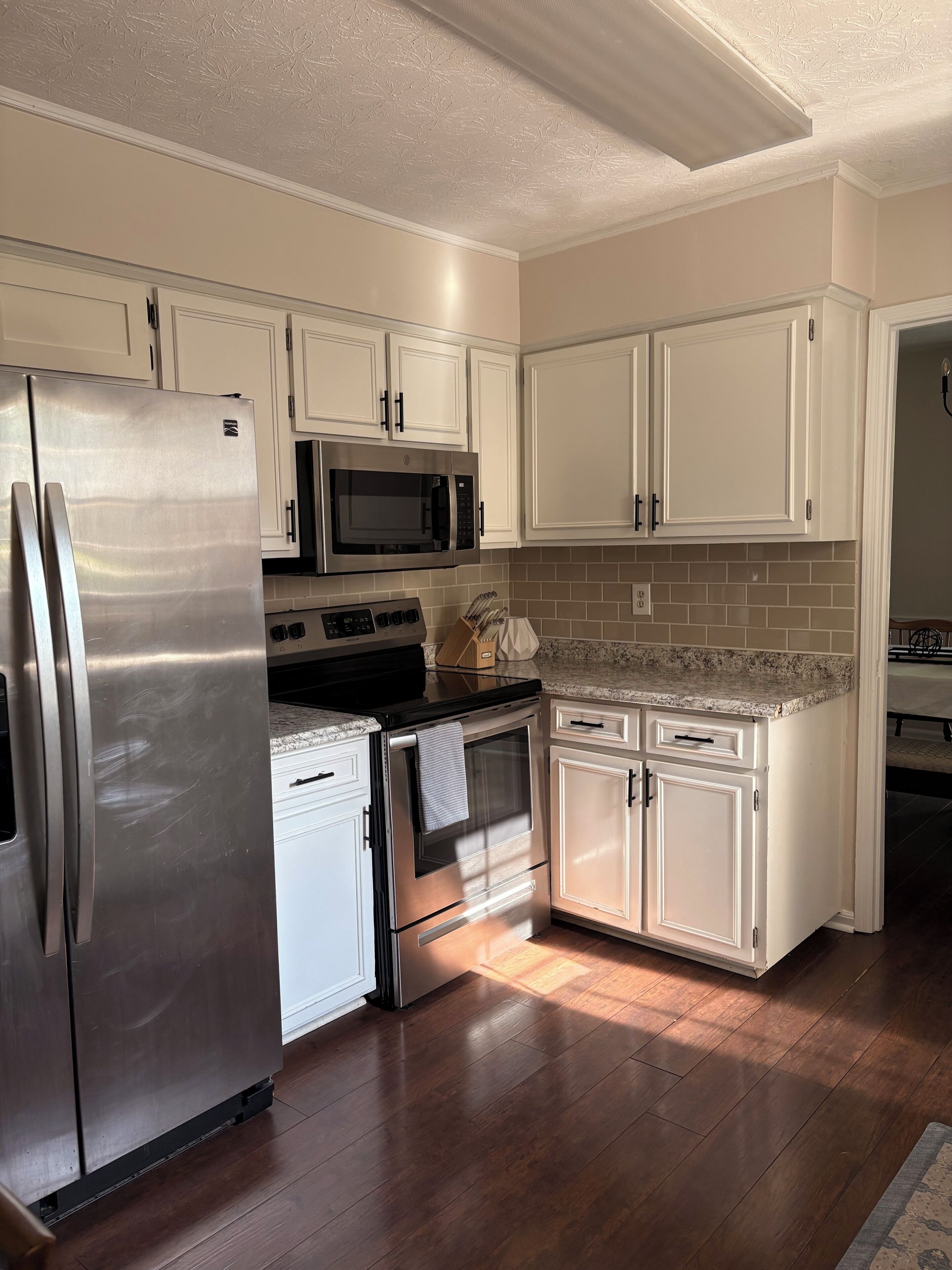 A kitchen with white cabinets, stainless steel appliances, a microwave, and a dishwasher.