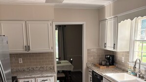 A kitchen with white cabinets, a granite countertop, a dishwasher, and a window with a view. - Relax and Unwind near West Point Lake (LaGrange)