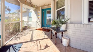 A covered outdoor area with a table and chairs, a potted plant, and a blue door. - Wonderful 4-bedroom building with AC in charming Port Charlotte (Port Charlotte)