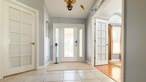 A hallway with a tiled floor, a ceiling fan, and a door leading to a room. - Wonderful 4-bedroom building with AC in charming Port Charlotte (Port Charlotte)