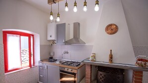A kitchen with a gas stove, oven, and a window with red frames. - Apartment not far from the center of Arezzo, suitable for both couples and families (Arezzo)