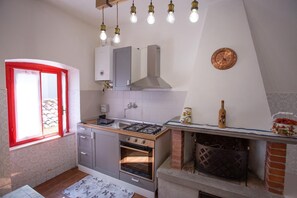 A kitchen with a gas stove, oven, and a window with red frames.