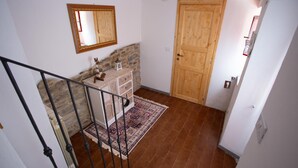 A staircase leading to a room with a stone wall, a wooden door, and a white dresser with a patterned rug. - Apartment not far from the center of Arezzo, suitable for both couples and families (Arezzo)