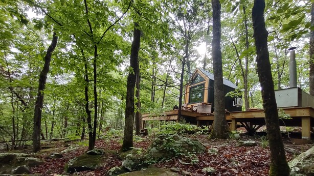 Eine Holzhütte im Wald mit einer Terrasse und einem Schornstein.
