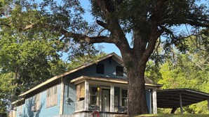 A two-story house with a porch, large tree, and a covered porch area. - Peaceful 3 bedroom home and room for 4 boats near Atoka, McGee, and Sardis Lake (Stringtown)
