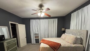 A bedroom with a bed, a dresser, a ceiling fan, and a window with curtains. - Peaceful 3 bedroom home and room for 4 boats near Atoka, McGee, and Sardis Lake (Stringtown)