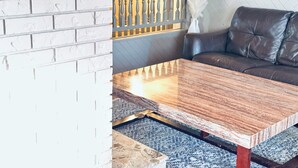 Une pièce avec un mur en briques, une table basse en bois, un canapé en cuir et un tapis à motifs.