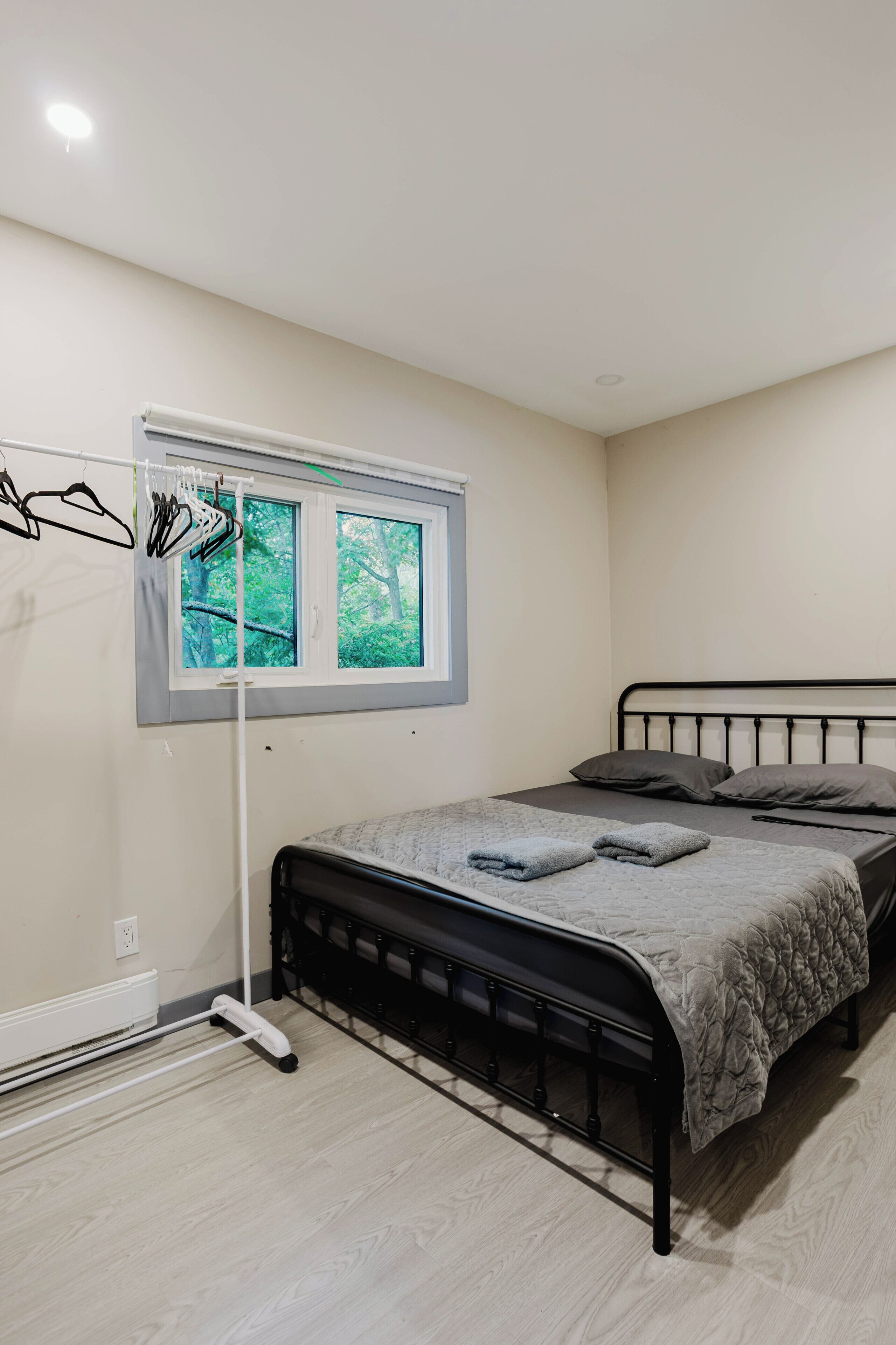 Une chambre avec un lit, une fenêtre, un radiateur et un étendoir.