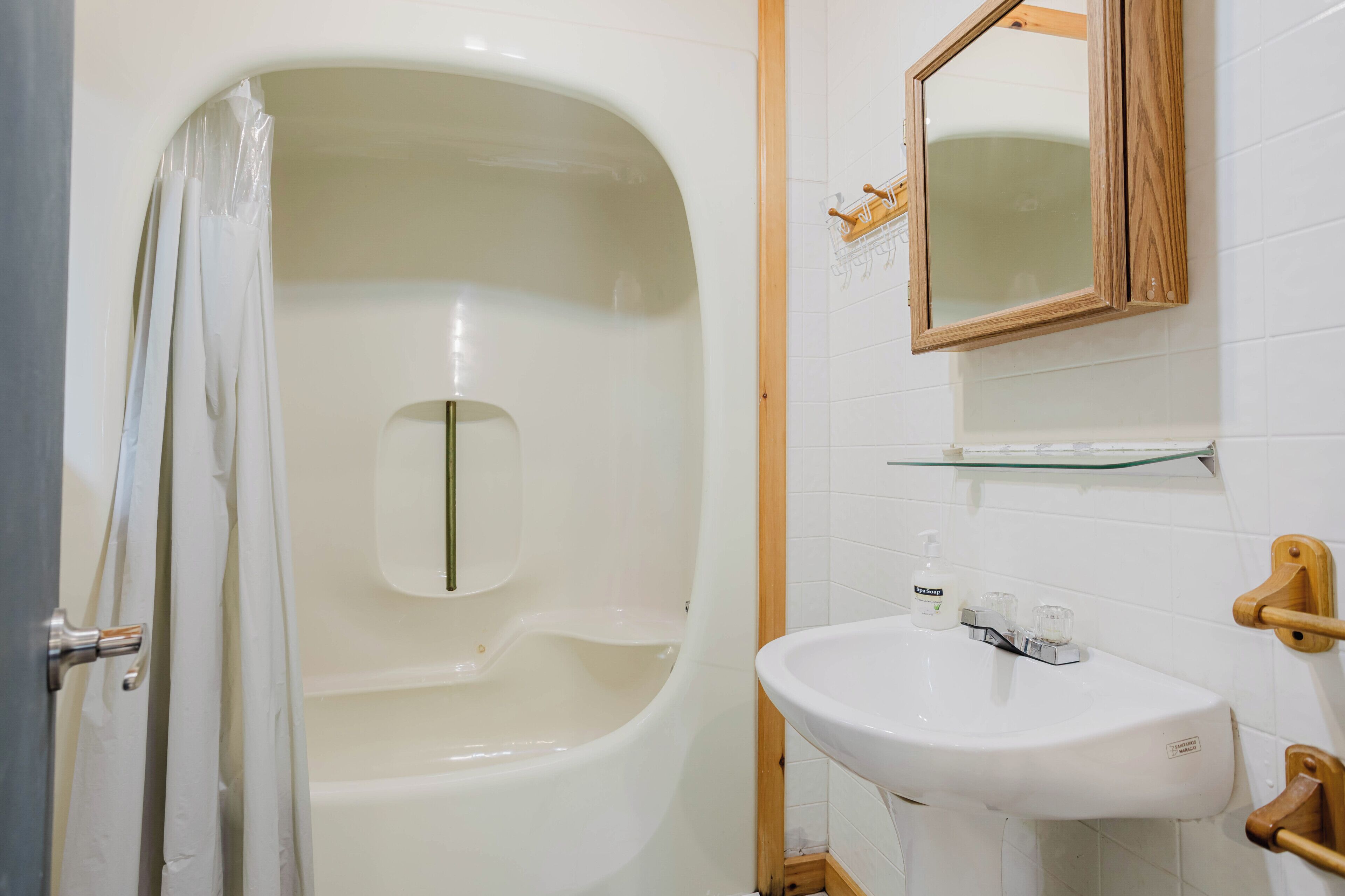 Une salle de bain avec une baignoire, un lavabo, un miroir et un rideau de douche.